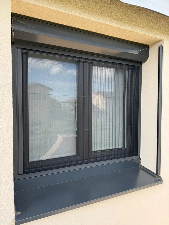 Moustiquaire accordéon gris anthracite posée sur une fenêtre